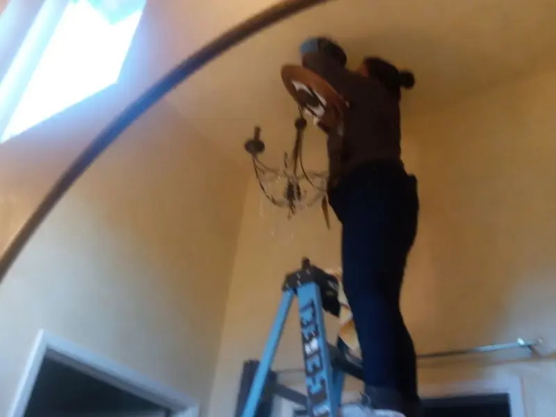 Electrician installing a chandelier in a Amberley residence